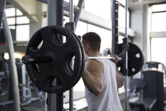 Rear View Of Young Man Lifting Weights In Gym
