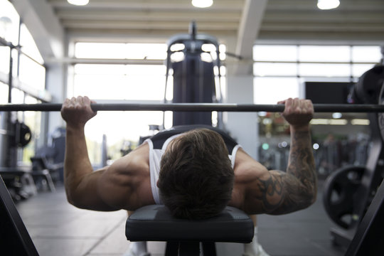 Man Bench Pressing Weights In Gym