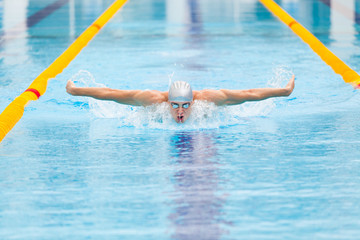 dynamic and fit swimmer in cap breathing performing the butterfly stroke