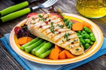 Grilled turkey fillet with vegetables on wooden background