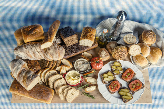 Stół zastawiony chlebem, warzywami, smalcem i przyprawami na śniadanie w kompozycji na tle obrusu