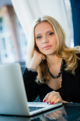 Unhappy female student tired of doing homework sitting at cafe with laptop