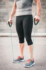 urban fitness man holding using expander. Sporty strong male working out outdoors.