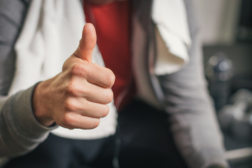 Successful fit man taking a workout rest. Male strong athlete resting after exercising workout doing success thumbs up gesture.