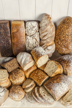Stos różnych chlebów, jasnych i ciemnych, pełnoziarnistych, obsypanych mąką - aranżacja