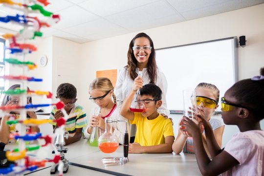 A teacher posing with pupils doing science