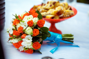 Fototapeta na wymiar A wedding bouquet of orange and white roses lies on a table