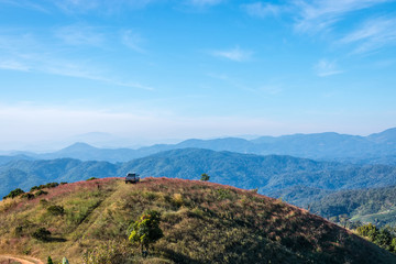 Naklejka premium Cars parked on a hill overlooking a beautiful mountain.