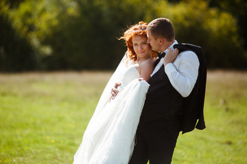 Stunning bride leans to a groom with her back while he kisses he