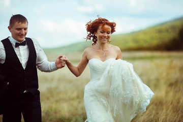 Fototapeta na wymiar Bride's curly hair mixes while she walks with a groom across the