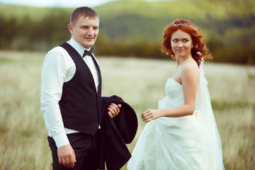 Happy wedding couple stand on the field