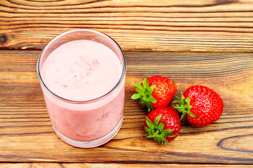Cup of strawberry yogurt and ripe strawberries on wooden table