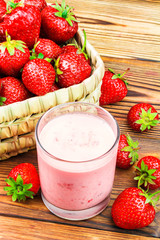 Cup of strawberry yogurt and ripe strawberries on wooden table