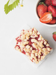 strawberry crumb bars with fresh red berries on grey background 