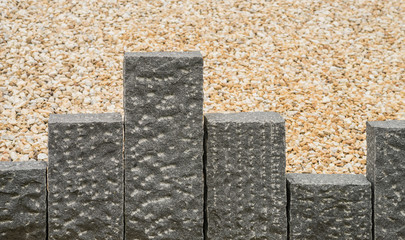 Dunkelgraue Stelen aus Granit vor beigefarbenem Steingranulat

- - - Dark gray steles granite before beige stone granulate