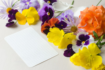 Colorful and beautiful flowers and a sheet of paper on the white background