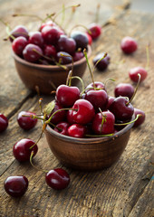 Ripe cherries in a clay bowl on wooden background