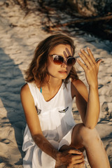 young girl sitting on the sand enjoying sunset
