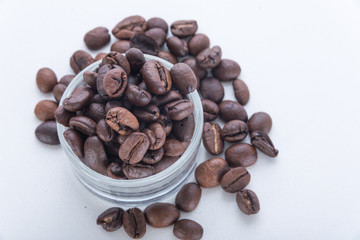 Roasted coffee beans in coffee shot glass and around