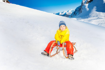 Fototapeta na wymiar Little boy on the sledge slide down hill 
