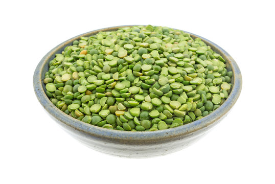 Bowl of organic green split peas isolated on a white background side view.