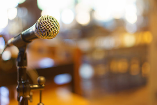 Microphone over the Abstract blurred photo of conference hall or