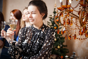 Portrait of beautiful young woman with glass of champagne celebrating new year with friends