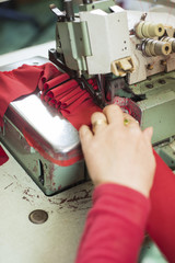 Hands of A Seamstress Stitching Red Cloth on Sewing Machine