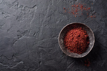 sumah or sumak - east spice in metal bowl on dark background. Selective focus. Top view.Background with place for some text