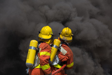 two firemen in fire fighting suit encounter with fire and black