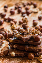 Chocolate and nuts: hazelnuts and walnuts on a wooden background, selective focus