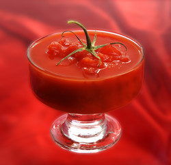 FRESH , RAW TOMATO SAUCE IN A GLASS ON RED SILK BACKGORUND