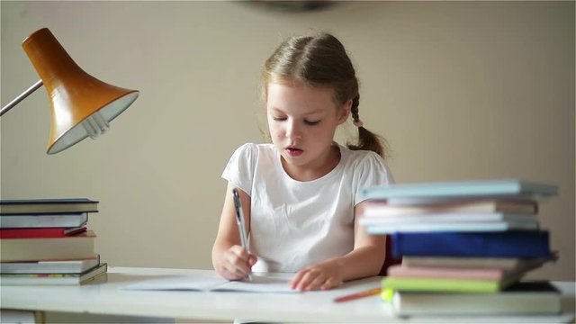 Schoolgirl doing homework and preparing for exams, cute children learning her lessons