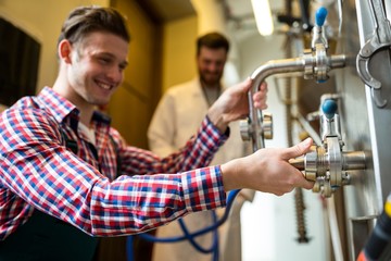 Maintenance workers examining brewery machine