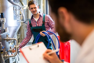 Maintenance workers examining brewery machine - Powered by Adobe