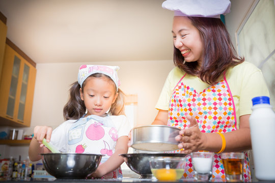 Asian mother and daughter enjoy making pancake, Asian mom teaching daughter to learn making pancake in real life kitchen at home