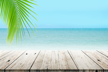 Fototapeta premium old wood table top on blurred beach background with coconut leaf