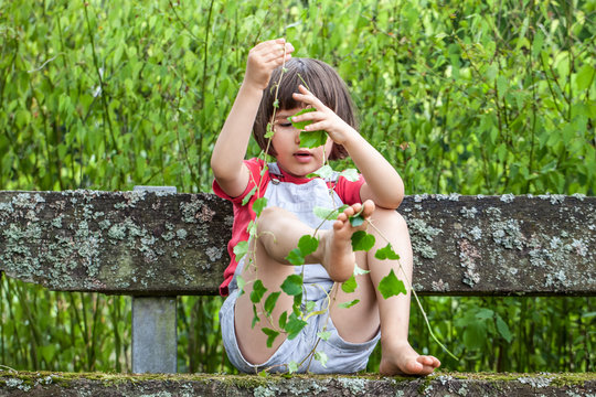 child playing with ivy foliage to learn nature in garden