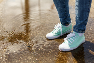 Woman in sport shoes standing in a puddle