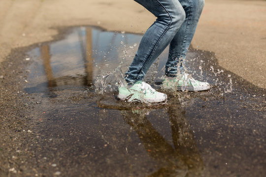 Woman in gumshoes jumping in a puddle