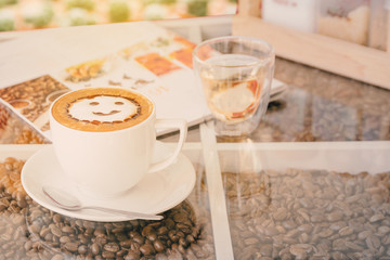 Vintage latte art  with smile shape milk foam in white coffee cup on table ,soft selected focus Cross process warm tone filter