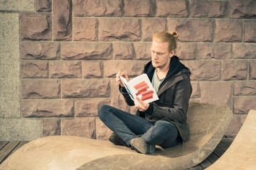 Young Handsome Man Reading on Stone Lounger