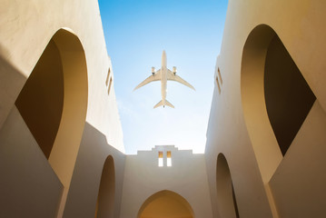 Aircraft over the arabic style yard of the house with white walls and clear blue sky