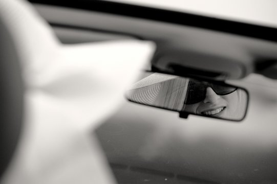 Junge Frau mit Sonnenbrille und Hut sitzt in einem Cabriolet