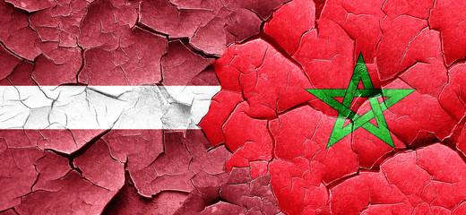 Latvia flag with Morocco flag on a grunge cracked wall