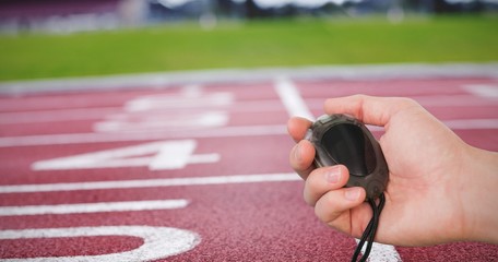Close up of coach is holding a stopwatch against race track - Powered by Adobe