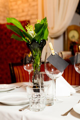 Birthday guests table setting with fresh flowers in black and gold style, indoor