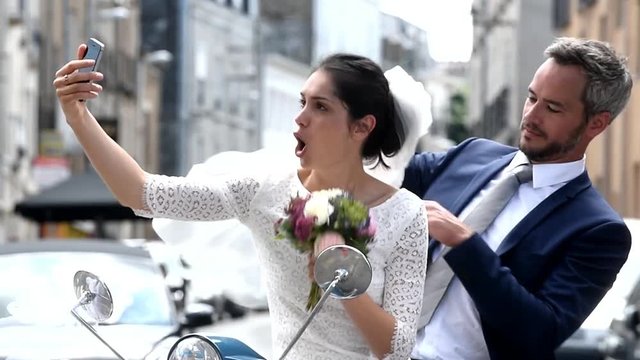 on a scooter,newlywed couple is making selfies with a smartphone 