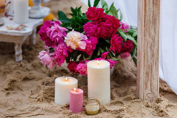 Beautiful, delicate wedding decorations with candles and fresh flowers on the beach