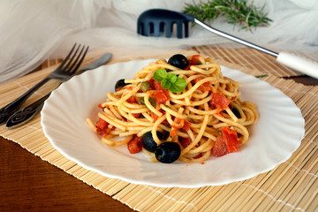 Delicious italian food spaghetti a la puttanesca on a bowl on a table.